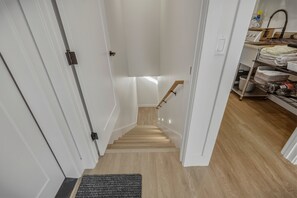 A narrow stairway leading to a landing with a wooden handrail and a black doormat at the bottom. - Mountain-view Pagosa Springs house on five acres with four bedrooms, three baths, private hot tub, two fireplaces, chef's kitchen, and entertainment room; sleeps 7. (Pagosa Springs)