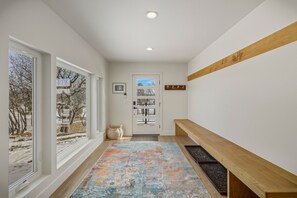 A hallway with a wooden bench, a door with a view of the outside, and a colorful rug. - Mountain-view Pagosa Springs house on five acres with four bedrooms, three baths, private hot tub, two fireplaces, chef's kitchen, and entertainment room; sleeps 7. (Pagosa Springs)