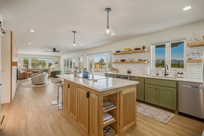 A modern kitchen with wooden cabinets, a central island, and a view of the outdoors through large windows. - Mountain-view Pagosa Springs house on five acres with four bedrooms, three baths, private hot tub, two fireplaces, chef's kitchen, and entertainment room; sleeps 7. (Pagosa Springs)