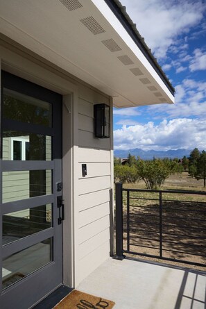 A modern building with a large glass door, a small black security camera, and a metal gate. - Mountain-view Pagosa Springs house on five acres with four bedrooms, three baths, private hot tub, two fireplaces, chef's kitchen, and entertainment room; sleeps 7. (Pagosa Springs)