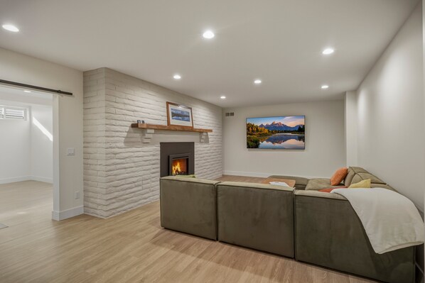 A modern living room with a fireplace, a large sofa, and a painting on the wall. - Mountain-view Pagosa Springs house on five acres with four bedrooms, three baths, private hot tub, two fireplaces, chef's kitchen, and entertainment room; sleeps 7. (Pagosa Springs)