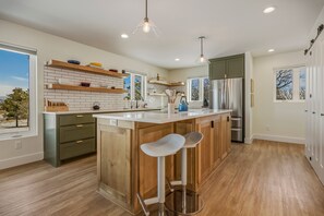 A modern kitchen with a central island, wooden bar stools, and built-in appliances. - Mountain-view Pagosa Springs house on five acres with four bedrooms, three baths, private hot tub, two fireplaces, chef's kitchen, and entertainment room; sleeps 7. (Pagosa Springs)