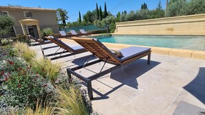 Un área de piscina con sillones de descanso y un deck con baldosas.