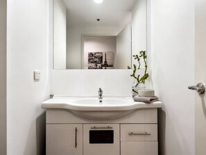 A modern bathroom with a white sink, a mirror, and a potted plant. - Adelaide Central Living! (Adelaide)