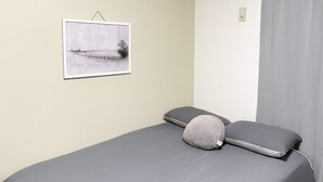 A single bed with grey bedding and two pillows, a framed picture on the wall, and a curtain on the window. - XeroB HOUSE FLOLIA602 (osaka naniwa ward nanbanaka)