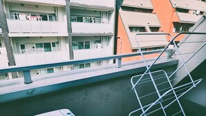 A balcony with a washing machine, a metal drying rack, and a view of a multi-story building with balconies. - XeroB HOUSE FLOLIA602 (osaka naniwa ward nanbanaka)