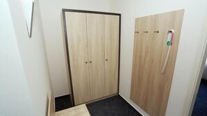 Ein Zimmer mit einem Holzschrank, einer kleinen Stufe zum dunklen Teppichboden und einem Lichtschalter an der Wand.