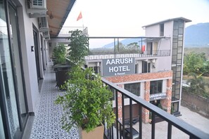 Un hotel llamado AARUSH HOTEL & RESORT con un diseño moderno, un balcón con plantas en macetas y vistas del paisaje circundante.