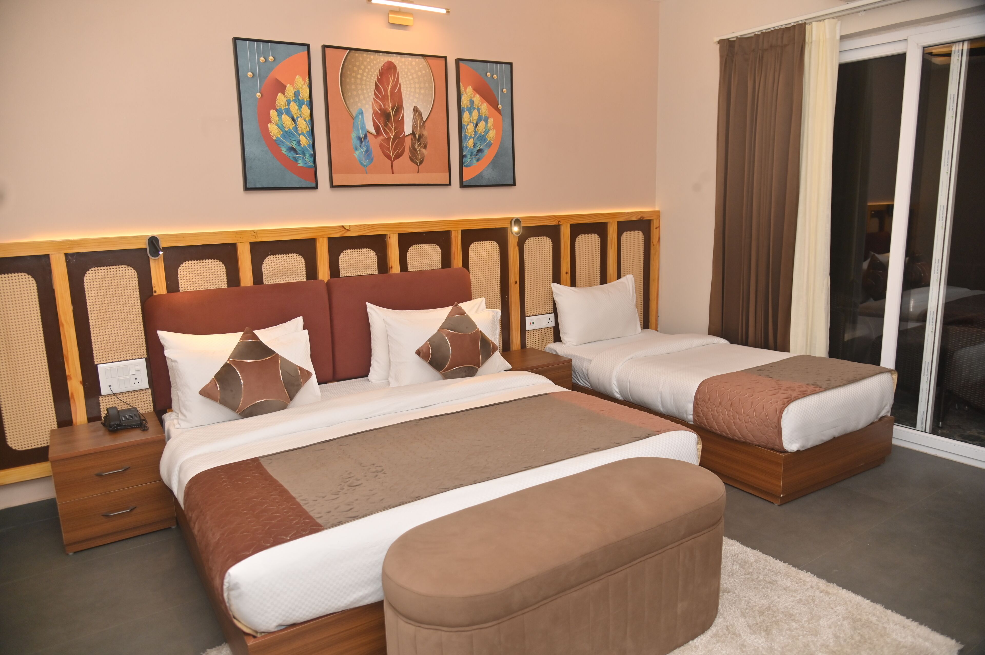 Een hotelkamer met twee bedden, een houten hoofdeinde, een groot raam met gordijnen en kunst aan de muur.