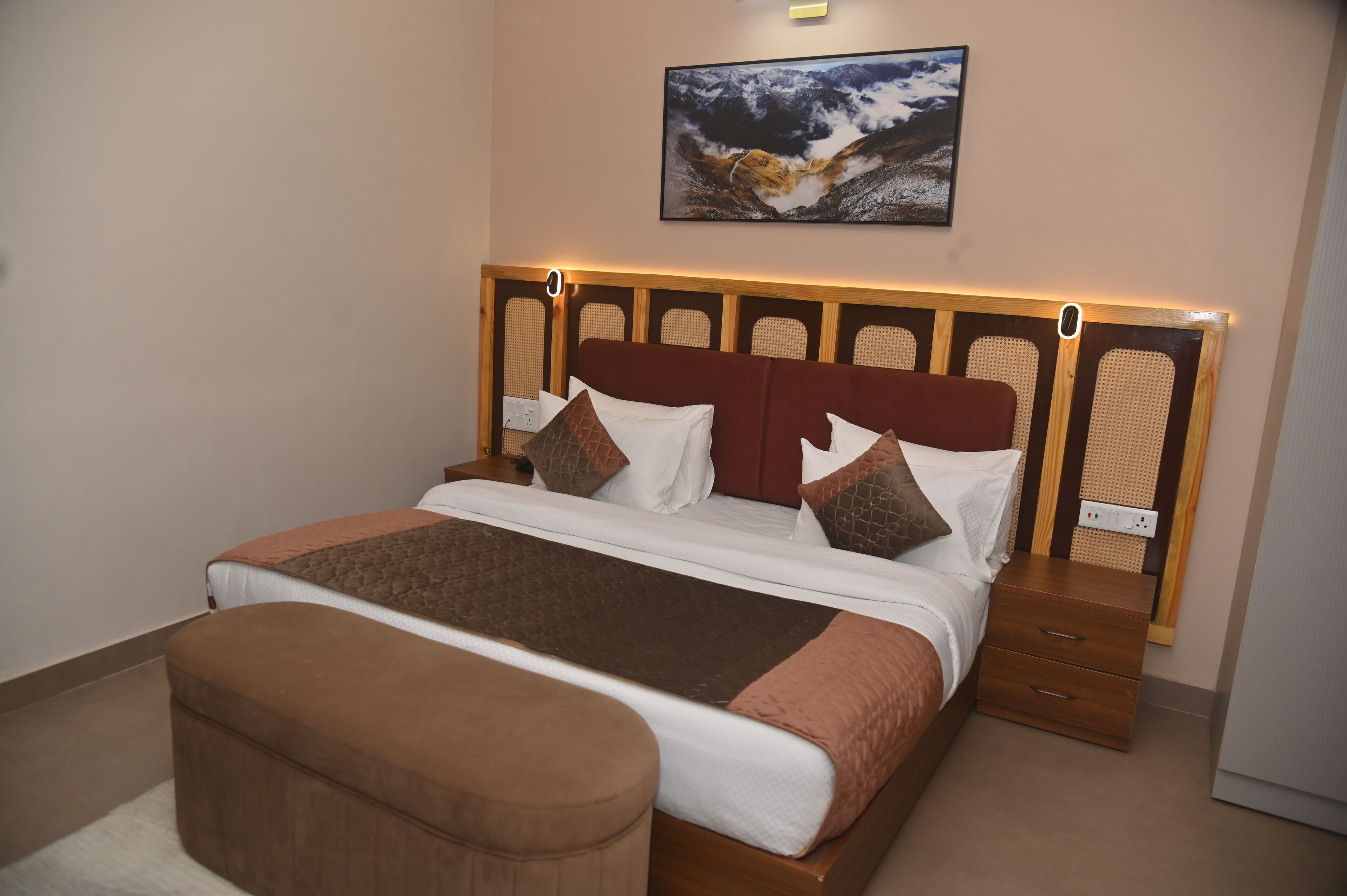 A neatly made bed with a wooden headboard, a bedside table, and a bench.