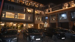 A multi-story hotel with a sign reading "Aarush Hotel." There are several cars parked in front, and the building has multiple balconies with railings. - AARUSH HOTEL & RESORT (Lalkuwa)