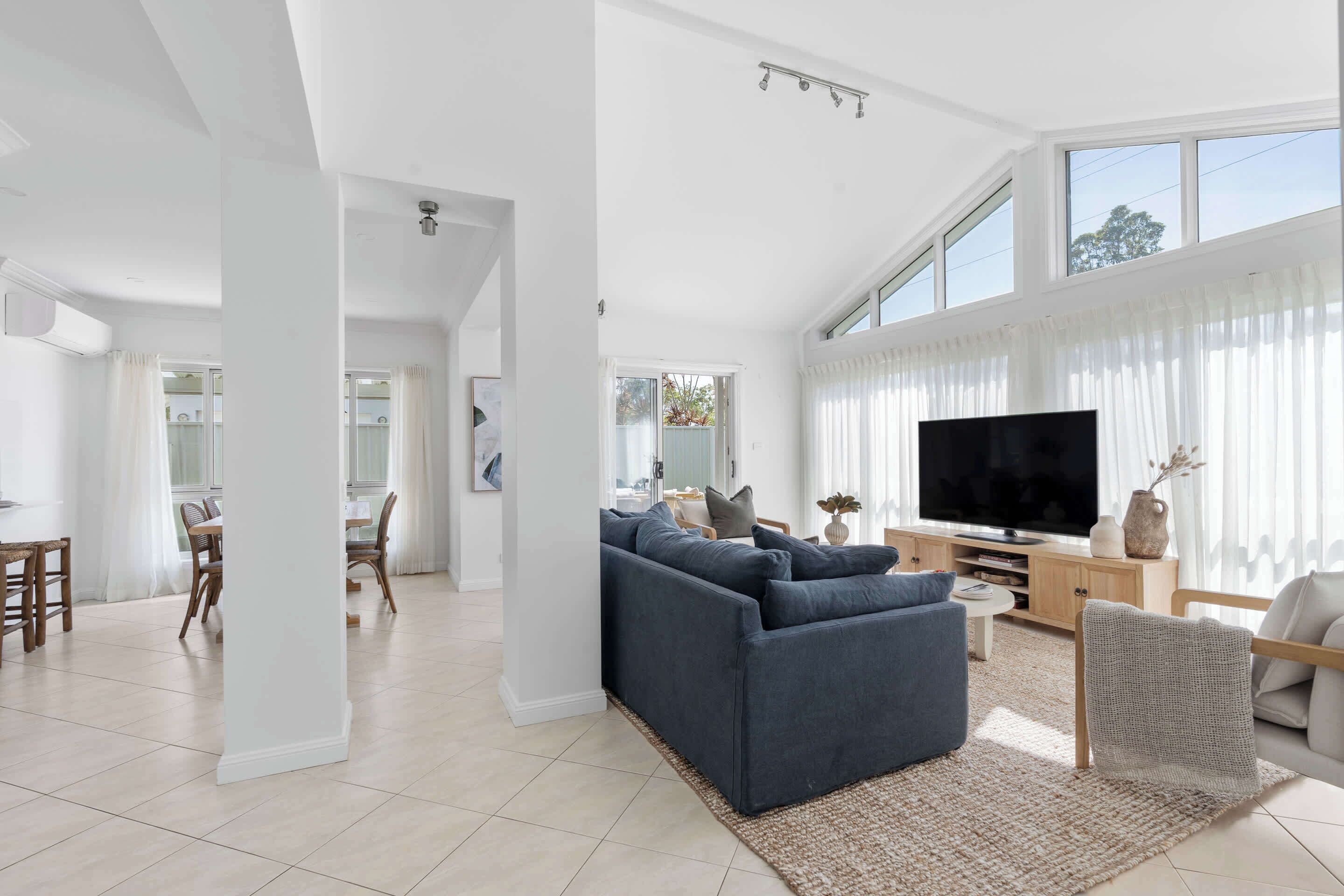 A spacious living room with a large TV, a sofa, and a dining area with chairs.