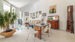A spacious living room with a glass dining table, a sofa, a coffee table, and a large potted plant. - Villa 'Casa Arola' with Sea Views, Wi-Fi and Air Conditioning (Sant Josep de sa Talaia)