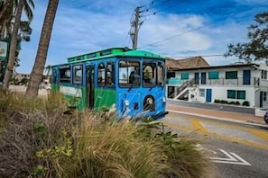 Un tranvía azul y verde circulando por una calle, con un edificio al fondo.