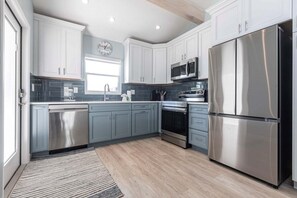 A modern kitchen with stainless steel appliances, grey cabinetry, and a wooden floor. - Villa 64 - Premium Plus (Siesta Key)