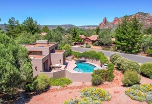 A modern house with a swimming pool surrounded by landscaped gardens and a view of red rock formations. - Peaceful Sedona Retreat, Views, Pool, Hot Tub! (Sedona)