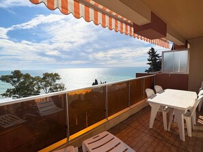 A balcony with a view of the sea, a table with chairs, and a TV mounted on the wall. - Apartment for 8 people with sea view and Wi-Fi in Roquebrune-Cap-Martin (Roquebrune-Cap-Martin)