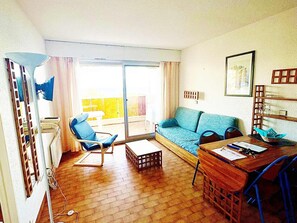 A living room with a sofa, a chair, a table, and a balcony with yellow railing. - Apartment for 8 people with sea view and Wi-Fi in Roquebrune-Cap-Martin (Roquebrune-Cap-Martin)