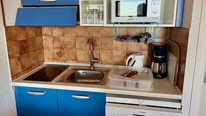 Eine kompakte Küche mit Mikrowelle, Kaffeemaschine und einem Geschirrspüler von Bosch.