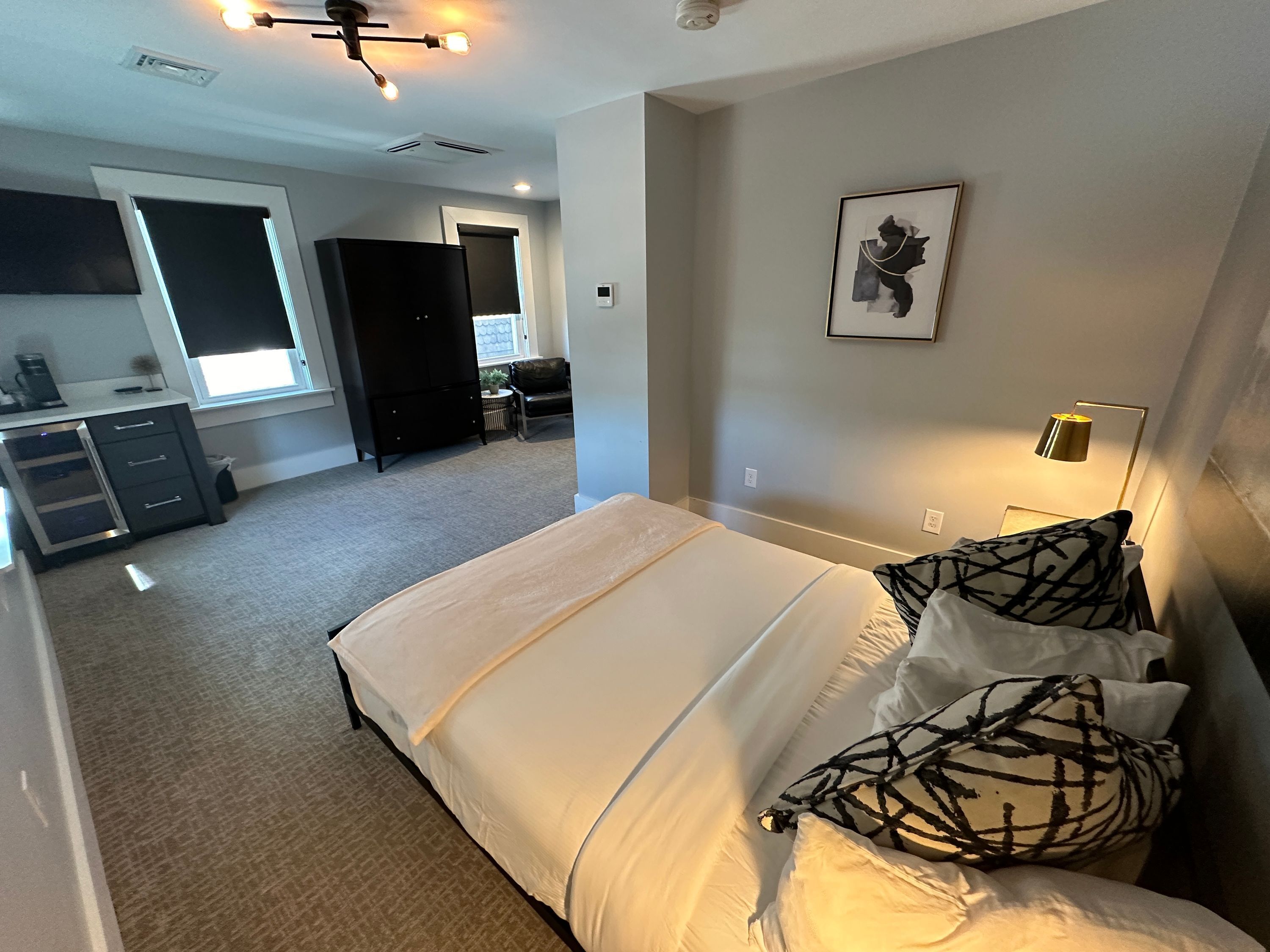 Ein Schlafzimmer mit einem großen Bett, einem Schreibtisch mit Stuhl, einem Kleiderschrank und einem Fenster.