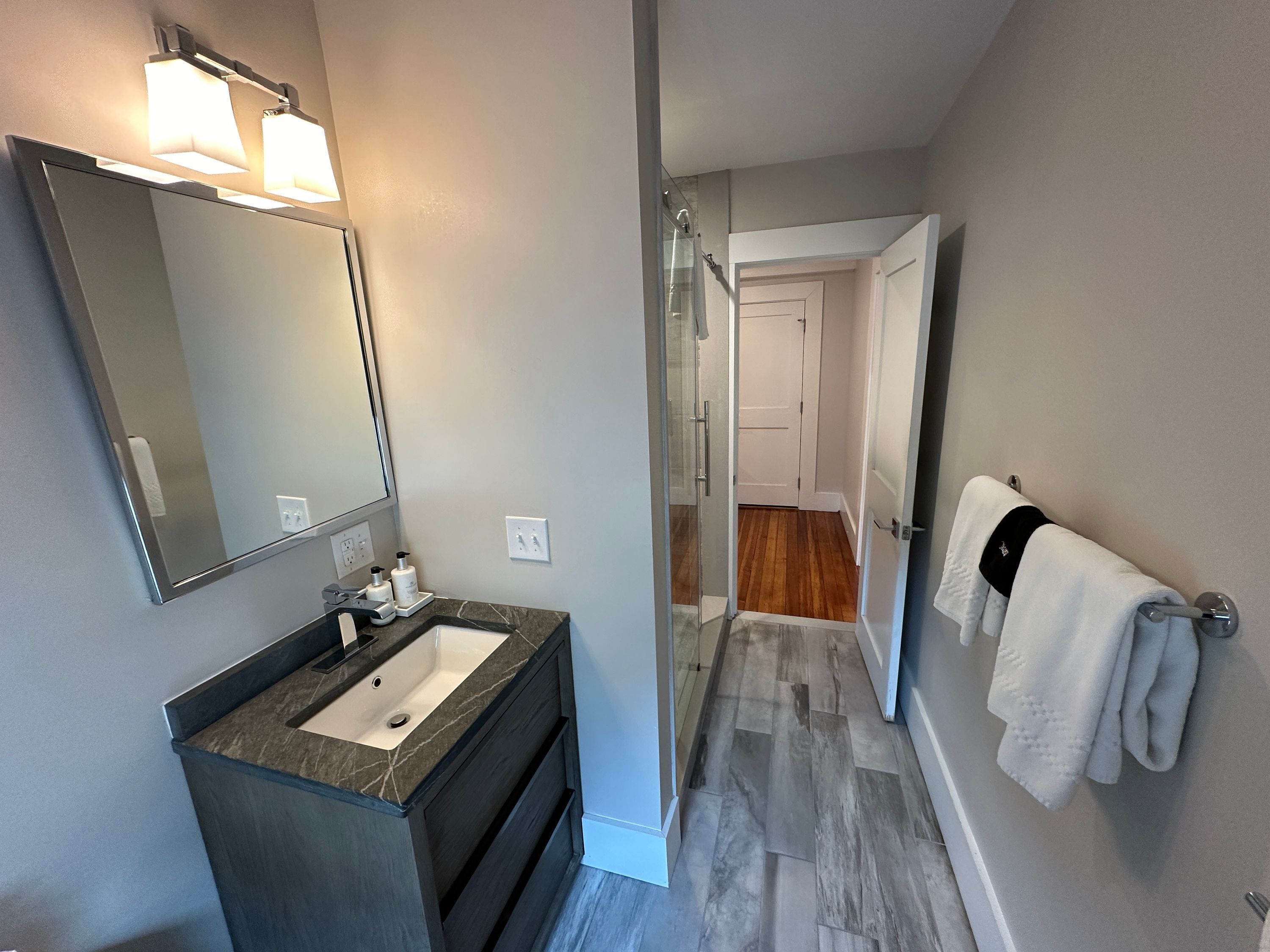 A modern bathroom with a large mirror, a sink, and a towel rack.