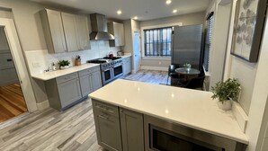 Una cucina moderna con mobili grigi, un piano di lavoro bianco ed elettrodomestici in acciaio inossidabile.