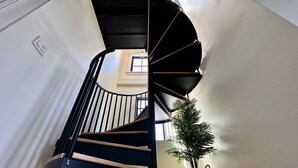 Eine Wendeltreppe mit schwarzen Geländern und Holzstufen, die zu einer oberen Etage führt.