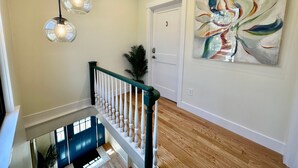 Eine Treppe mit Holzvertäfelung, eine weiße Tür mit der Nummer 3 und ein modernes abstraktes Gemälde an der Wand.