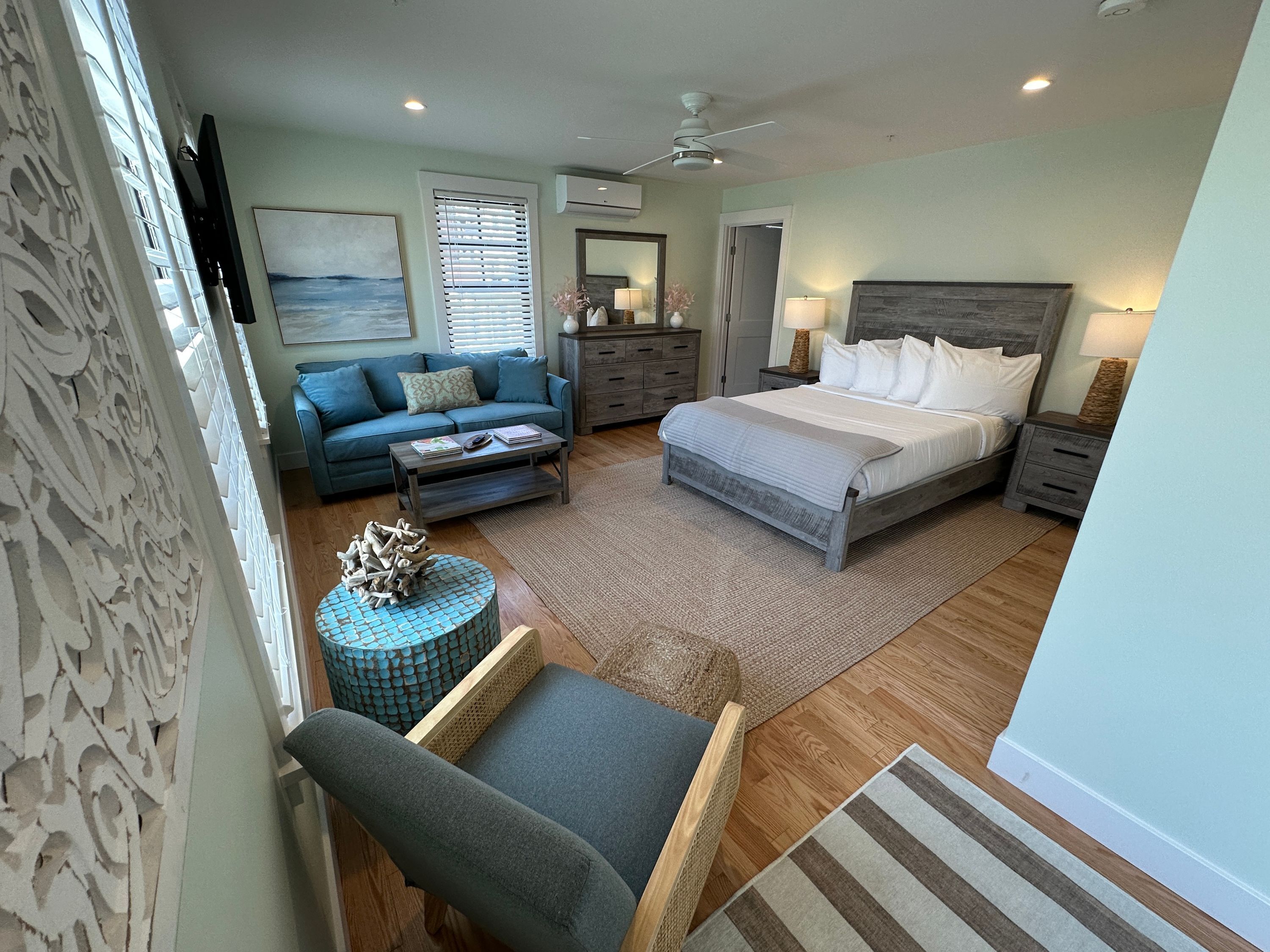 A bedroom with a bed, nightstands, a dresser, a sofa, and a coffee table.