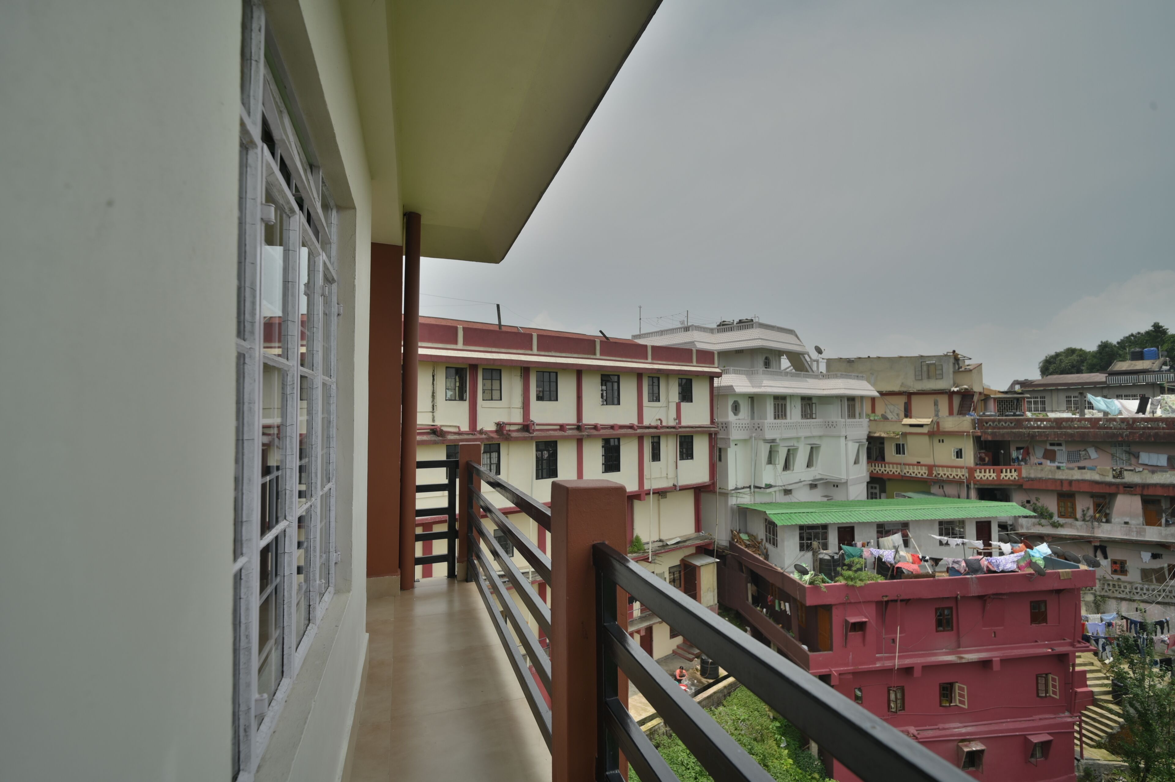 Un balcone con vista su edifici a più piani, una ringhiera e una finestra con grate.