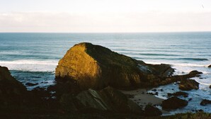 Paesaggio costiero con una formazione rocciosa imponente e l'oceano.