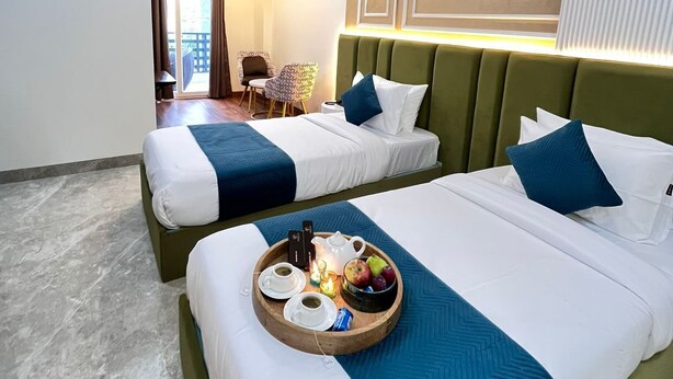 Ein Hotelzimmer mit zwei Betten, einem Deckenventilator und einem Frühstücksbrettchen auf dem Bett.