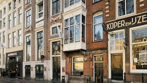 A row of buildings with distinct architectural styles, including a black-framed window and a sign for 'KoperenJuze'. - Supper boutique suites (Amsterdam)