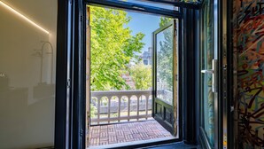 An open door to a balcony with a view of trees and buildings. - Supper boutique suites (Amsterdam)