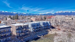 A modern apartment complex with multiple balconies, situated near a rocky stream and snow-capped mountains in the background. - Spacious 2BDRM, 2BA on the quiet edge of downtown Salida, Mountain Views, 2 blocks to shops (Salida)