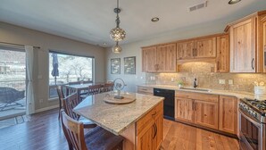 A kitchen with wooden cabinets, granite countertops, a built-in oven, and a dining area with chairs and a table. - Spacious 2BDRM, 2BA on the quiet edge of downtown Salida, Mountain Views, 2 blocks to shops (Salida)
