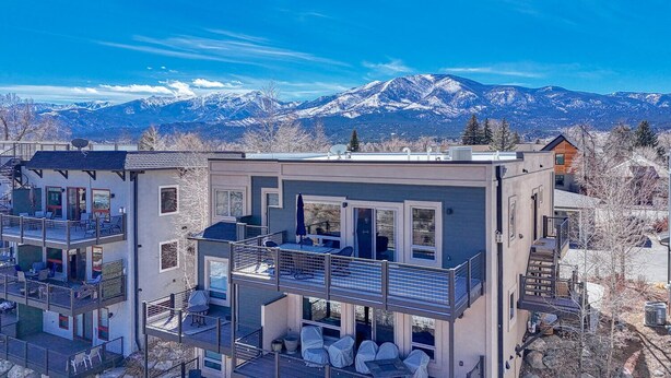 A modern multi-story building with balconies, large windows, and a view of snow-capped mountains. - Spacious 2BDRM, 2BA on the quiet edge of downtown Salida, Mountain Views, 2 blocks to shops (Salida)