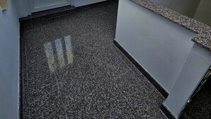 Una stanza con soffitto spiovente, una finestra con vetro smerigliato, una porta e un piccolo pannello bianco fissato alla parete.