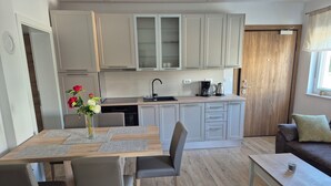 Una cucina moderna con mobili grigi, un tavolo da pranzo con sedie, una macchina per il caffè e una finestra con vista.