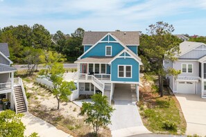 A two-story house with a balcony, a covered porch, and a driveway. - Santorini Blue 5 Bedroom Home at Monteray Shores (Corolla)