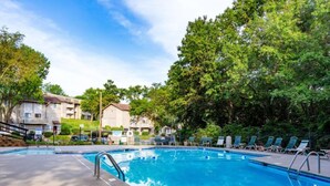 A rectangular swimming pool with a clear blue water surface, surrounded by lounge chairs and a paved deck. - Comfortable stay with smart layout (Kansas City)