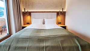 A modern hotel room with a large bed, wooden headboard, two bedside tables, and a view of the outdoors. - Aparthotel Iris by Interhome (Auffach)