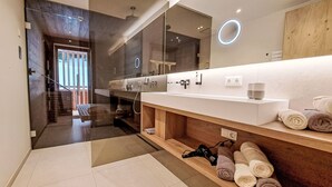 A modern bathroom with a large mirror, a vanity with a white countertop, and a towel rack with neatly rolled towels. - Aparthotel Iris by Interhome (Auffach)