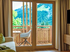 A room with a bed, a chair, and a wooden balcony with a view of a forest and mountains. - Aparthotel Iris by Interhome (Auffach)