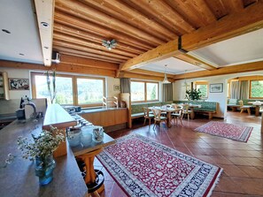 A spacious room with a high ceiling, wooden beams, a dining area with a table and chairs, and a kitchen area with a counter and sink. - Aparthotel Iris by Interhome (Auffach)