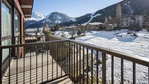 Een houten balkon met uitzicht op een besneeuwd landschap en bergen op de achtergrond.