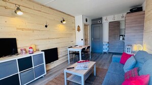 Ein modernes Wohnzimmer mit einer Holzwand, einem Sofa, einem Couchtisch und einem Fernseher.