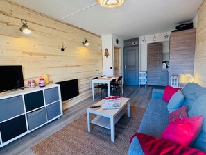 A modern living room with a wooden wall, a sofa, a coffee table, and a TV. - Renovated apartment in central Les 2 Alpes, near slopes (Les Deux Alpes)