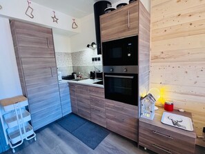 A compact kitchen with wooden cabinets, a built-in oven, and a sink. - Renovated apartment in central Les 2 Alpes, near slopes (Les Deux Alpes)