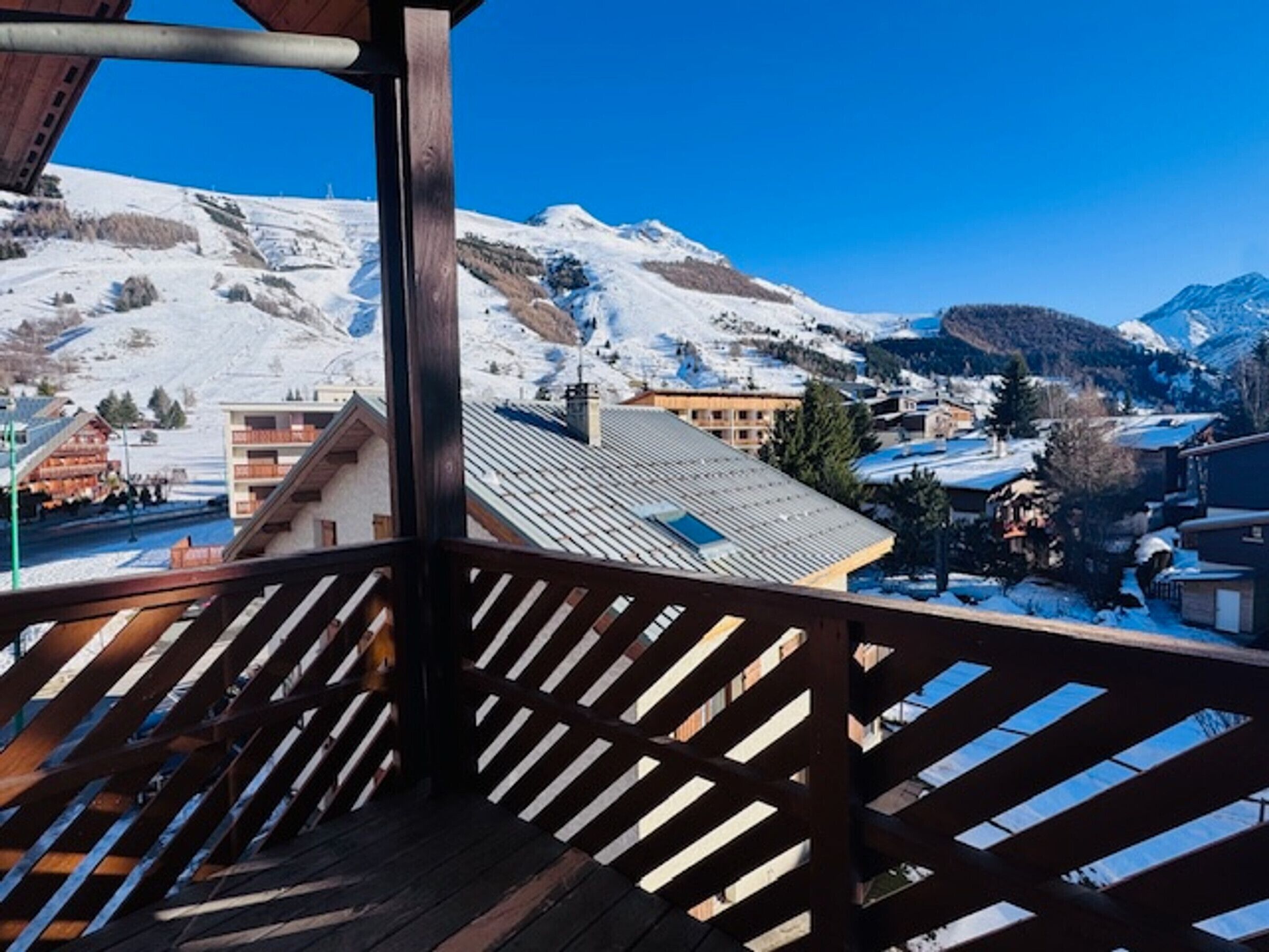 Un balcón de madera con vistas a un pueblo cubierto de nieve.